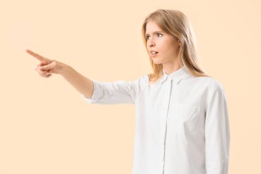 Bej arka planda bir şeye işaret eden genç bir kadın. Suçlama kavramı