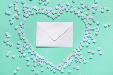 Zarflı kompozisyon ve renk arkaplanlı kalp şeklinde cam taşlar. Sevgililer Günü kutlaması