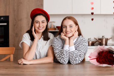 Sevgililer Günü 'nde mutfaktaki masada oturan genç lezbiyen çift