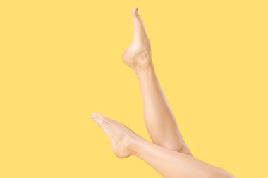 Sarı arka planda yalınayak bir kadın.