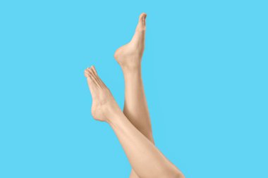 Mavi arka planda çıplak ayaklı kadın.