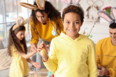 Paskalya yumurtası ve ailesi evde olan küçük Afro-Amerikalı çocuk.