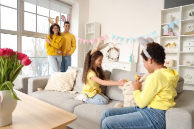 Küçük çocuklar evdeki kanepede paskalya yumurtası arıyorlar.