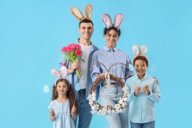 Paskalya çelengi ve mavi arka planda laleleri olan tavşan kulaklı mutlu bir aile.