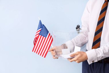 Elinde oy sandığı ve arka planda ABD bayrakları olan bir adam var. Seçim kavramı
