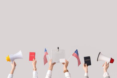 Beyaz arka planda oy sandığı, Amerikan bayrakları, pasaportlar ve megafonlar tutan eller. Seçim kavramı