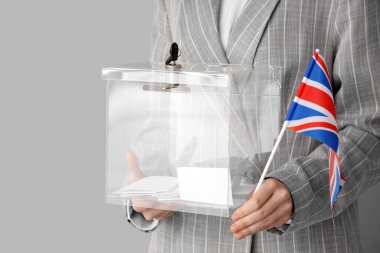 Beyaz arka planda oy sandığı ve İngiliz bayrağı tutan bir kadın. Seçim kavramı