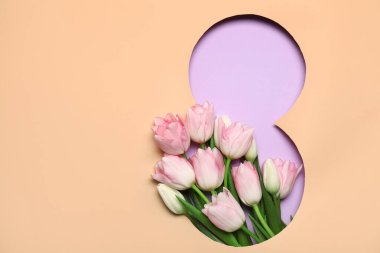 Mor arka planda güzel lale çiçekleri olan, şekil 8 şeklinde bej bir kağıt kes. Uluslararası Kadınlar Günü