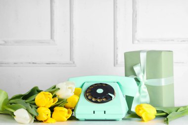 Retro telefon, güzel laleler ve beyaz masanın üzerinde hediye kutusu. Uluslararası Kadınlar Günü