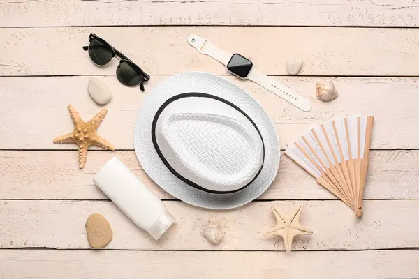 Composition with beach accessories and smart watch on light wooden background