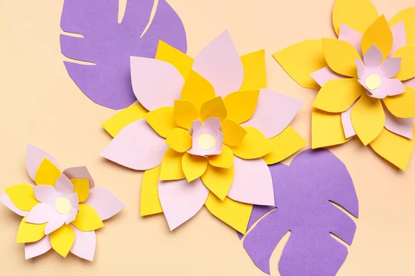 Colorful origami flowers and leaves on beige background