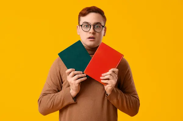 Emotionaler Junger Mann Mit Büchern Auf Gelbem Hintergrund — Stockfoto