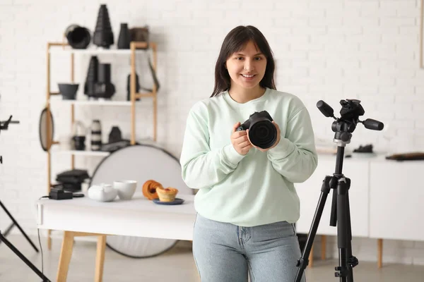 Female food photographer with camera in studio