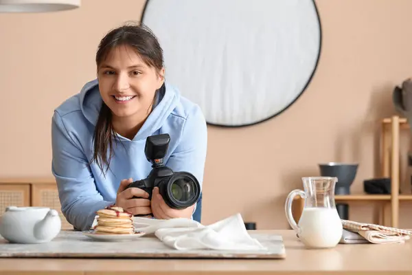Female food photographer with camera shooting tasty pancakes in studio
