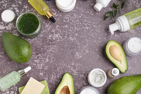 Taze avokadodan yapılmış çerçeve ve grunge arka planında farklı kozmetik ürünler
