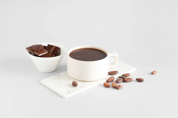 Cup of tasty hot chocolate with cocoa beans on white background