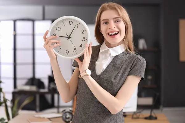 Young businesswoman with clock in office. Time management concept