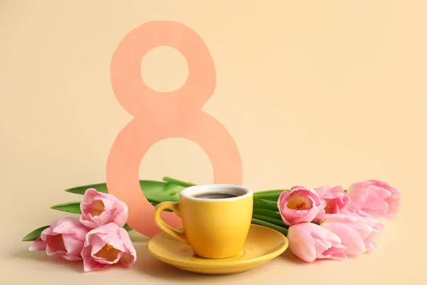 Tulip flowers with cup of coffee and paper figure 8 on beige background. International Women's Day celebration