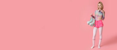 Pembe arka planda eski paten ve kulaklıkları olan, mesaj atmak için yeri olan güzel genç bir kadın.