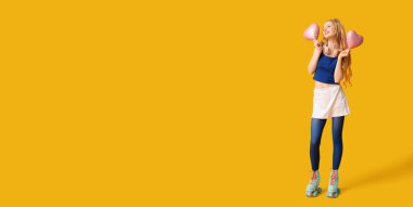 Eski paten giyen mutlu genç bir kadın ve sarı arka planda kalp şeklinde balonları ve mesaj için yeri olan bir kadın.