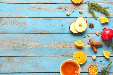 Lezzetli sıcak şarap ve bir kase bal hazırlamak için gerekli malzemeler mavi ahşap arka planda.