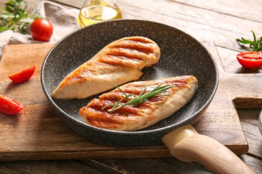 Lezzetli ızgara tavuk göğsü, biberiye ve ahşap arka planda domatesler.