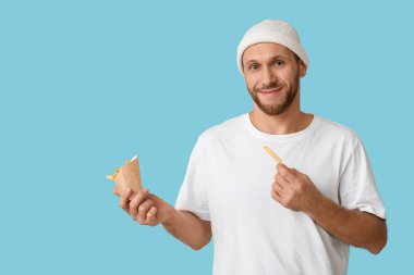 Mavi arka planda patates kızartması olan genç adam.