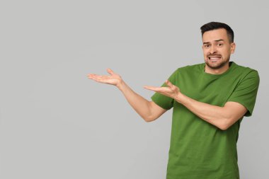 Yakışıklı endişeli genç adam gri arka planda bir şeye işaret ediyor.