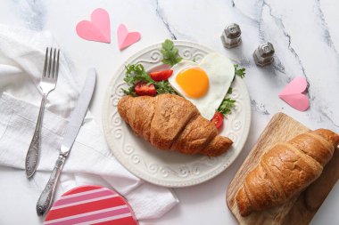 Lezzetli kızarmış yumurta, kruvasan, domates ve roka karışımı.