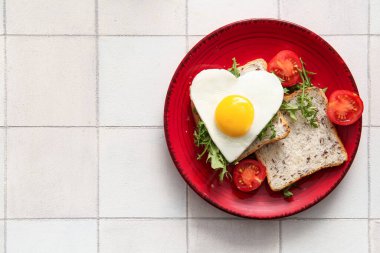 Hafif fayanslı yumurta, tost, domates ve roka tabağı.
