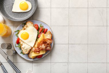 Lezzetli kızarmış yumurta, kruvasan, pastırma, domates ve açık fayanslı bir bardak meyve suyu karışımı.