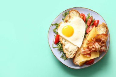 Lezzetli kızarmış yumurta, kruvasan, domates ve turkuaz kaplama roka.