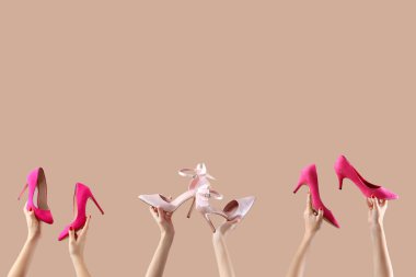 Bej arka planda farklı ayakkabılar tutan kadın eller.