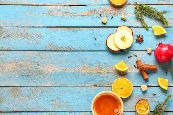 Lezzetli sıcak şarap ve bir kase bal hazırlamak için gerekli malzemeler mavi ahşap arka planda.