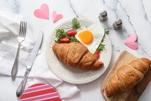 Lezzetli kızarmış yumurta, kruvasan, domates ve roka karışımı.