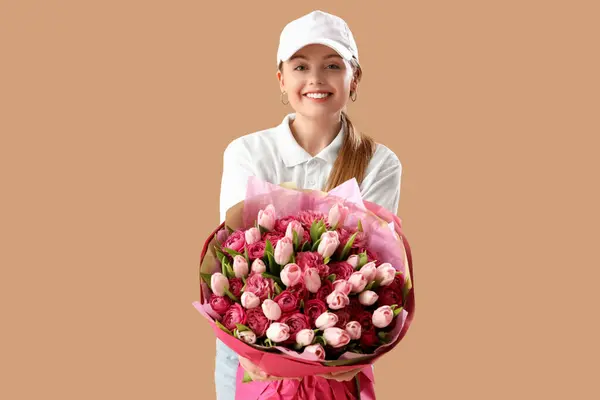 Female courier with bouquet of flowers on brown background