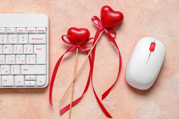Computer keyboard with mouse and heart shaped decor on beige grunge background. Concept of online dating