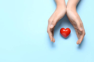 Mavi arka planda kırmızı kalpli kadın elleri
