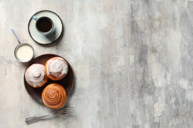 Tarçınlı çörekler, krema ve kahve ile gri grunge arka plan