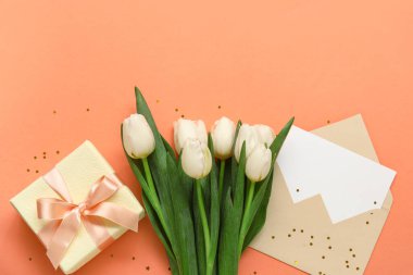 İçinde boş kart, hediye kutusu ve turuncu arka planda beyaz laleler olan zarf.