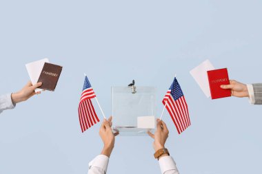 El ele tutuşan oy sandığı, pasaportlar, ABD bayrakları ve arka planda oylama kağıtları. Seçim kavramı