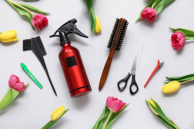 Gri arka planda güzel laleleri olan kuaför aletleri.