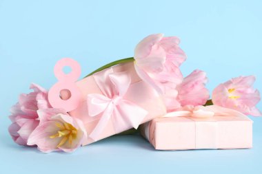 Hediye kutuları ve mavi arka planda güzel pembe laleleri olan kağıttan yapılmış 8 figür. Uluslararası Kadınlar Günü