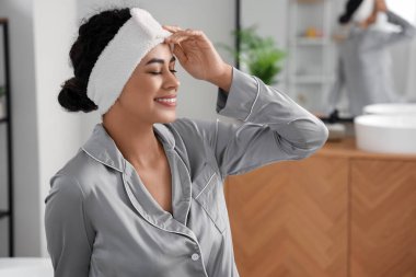 Banyoda saç bandı takan Afro-Amerikalı genç bir kadın.