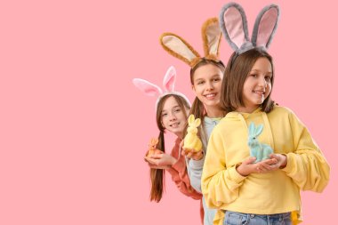 Paskalya tavşanı kulakları ve pembe arka planda oyuncak tavşanları olan sevimli küçük bir kız.