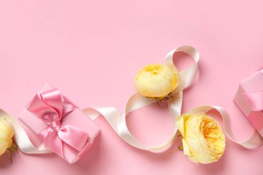 Kurdele, hediye kutuları ve pembe arka planda şakayık tomurcukları olan sekiz figürlü kompozisyon. Uluslararası Kadınlar Günü kutlamaları