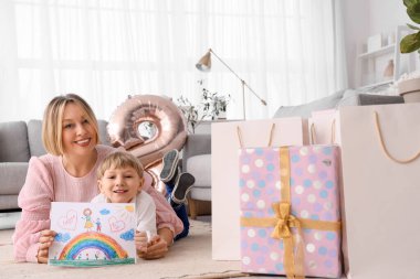 Evde yerde yatan annesi için çizim yapan küçük bir çocuk. Uluslararası Kadınlar Günü