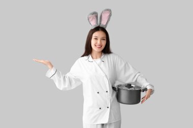 Tavşan kulaklı, hafif arka planda tenceresi olan Asyalı bir kadın şef. Paskalya kutlaması