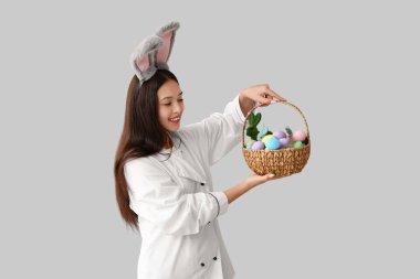 Paskalya yumurtaları hafif arka planda tavşan kulaklı Asyalı kadın şef.