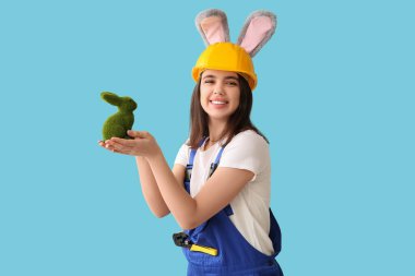 Mavi arka planda Paskalya tavşanı olan tavşan kulaklı kadın işçi.